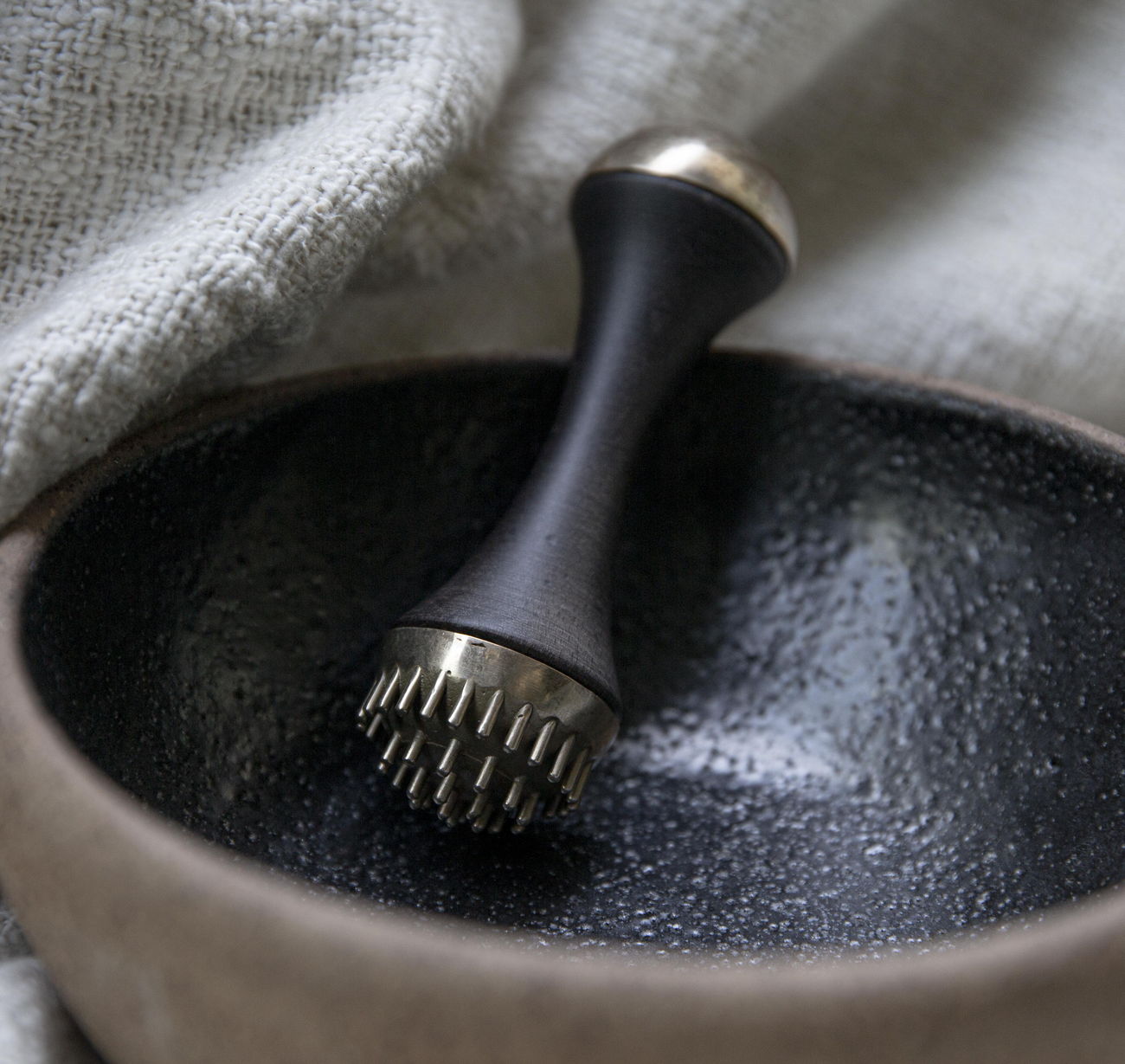 A Chinese medicine stone bowl and tool resting on folded linen